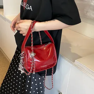 Detail of red patent leather cylinder bag with silver chain strap and fashion label