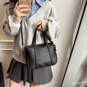 Detail of black lychee grain leather handbag featuring dual handles and silver hardware