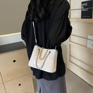 Detail view of cream white bucket bag with silver chain and leather strap on model