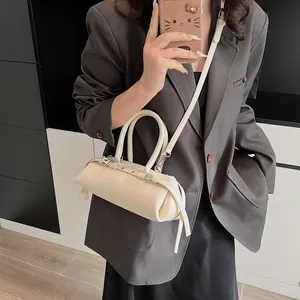 Detail of cream baguette bag with tassel drawstrings, double handles and slim shoulder strap