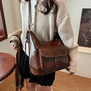 Detailed close-up of dark brown vintage gloss leather shoulder bag with buckle pocket