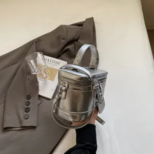 Silberne Metallic-Zylindertasche in der Hand, mit strukturierter Optik und Tragegriff