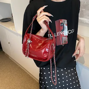 Detail of red patent leather square handbag with silver chain and FASHION label