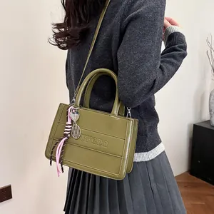 Olive green tote bag with parallel embossed lines and decorative charms in a side view
