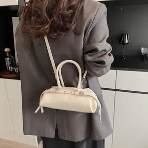 Detail of cream white leather baguette bag worn with a grey oversized blazer