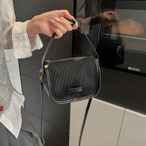 Detail der schwarzen Handtasche mit vertikalen Falten und goldenen Beschlägen