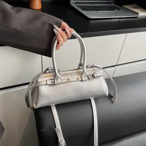 Detailed side view of silver baguette bag with metallic eyelets and strap on a desk