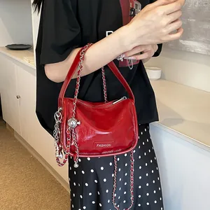 Detail of red glossy patent leather bag with silver chain and Fashion metal plaque