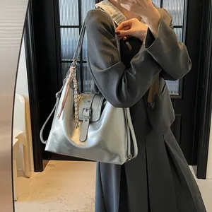 Silver metallic bucket bag with belt buckle detail and decorative charms on model