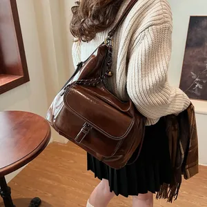 Detail of vintage brown leather handbag with metallic buckle and flap pocket for daily commute