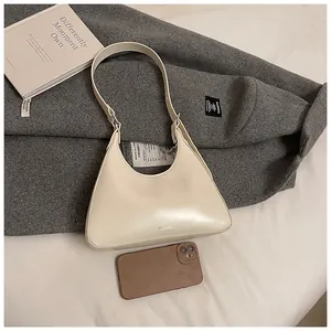 Detailed view of cream-white half-moon shoulder bag with minimalist brand logo and metal buckle