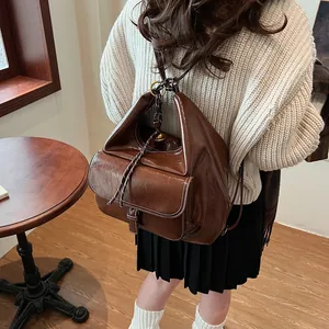 Detail of vintage brown leather backpack showing oily texture and drawstring closure