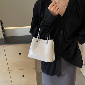 Detail of glossy cream leather bucket bag with silver chain handle for stylish urban look
