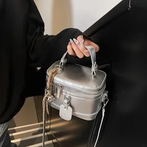 Detailansicht der silbernen Metallic-Box-Tasche mit Knotendekor und Logo-Anhänger