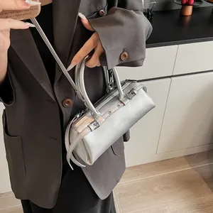 Detailed view of silver metallic Boston bag with decorative buckle straps and studs