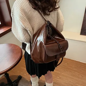 Detail of dark brown vintage backpack showing high-gloss leather and contrast stitching