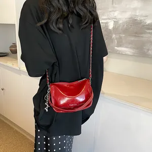 Close-up of vibrant red patent leather crossbody bag with silver chain and FASHION logo