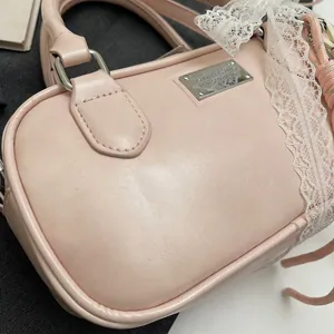 Detail of pink PU leather bowling bag with white lace trim and silver brand plate