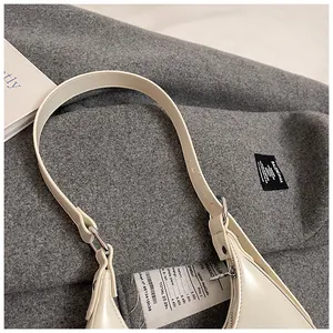 Detail shot of a minimalist cream hobo bag with a creative paper tag and silver hardware
