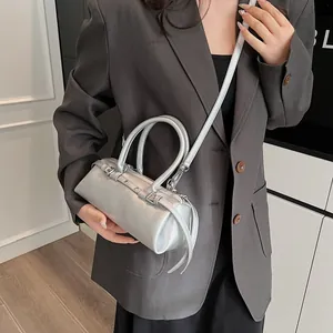 Silver cylinder bag with metal texture and shoulder strap shown on a model
