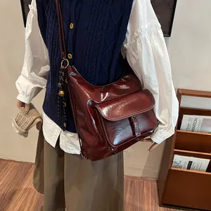 Close-up of wine red glossy leather tote with buckled pocket on a vintage outfit