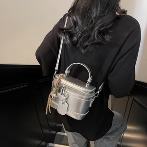 Silberne Box-Umhängetasche mit Metallic-Finish und Griff, am Model präsentiert