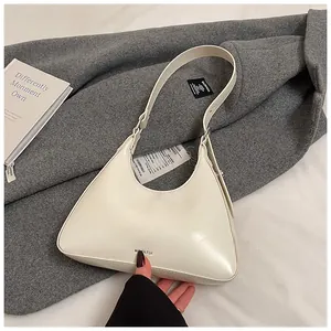 Detail of cream white half-moon underarm bag with NO FILTER print on dark wool coat