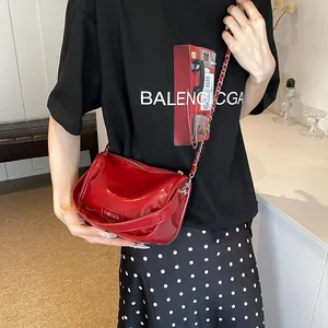 Detail of red patent leather shoulder bag with silver chain and metal fashion tag