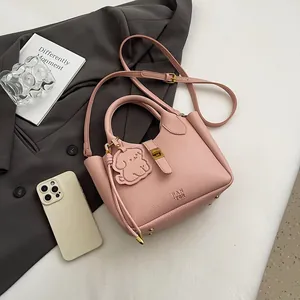 Vue détaillée du sac seau rose en cuir grainé avec boucle en métal et pendentif d'ours
