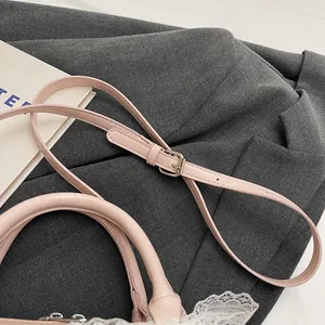 Detail of pink leather handbag with white lace trim and adjustable silver hardware strap