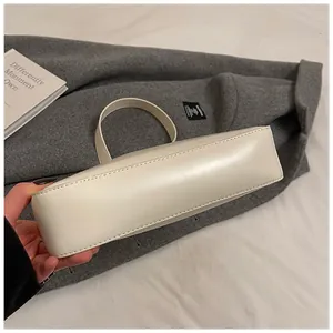 Detail of cream leather shoulder bag with fine stitching on wool coat background