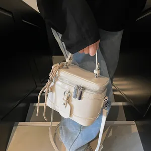 Detail der cremeweißen Box-Tasche mit Doppelreißverschluss und geflochtenem Ornament