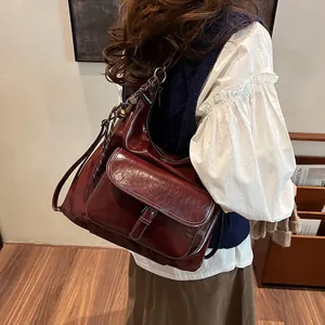 Detailed view of burgundy vintage leather shoulder bag with buckle pocket and glossy texture