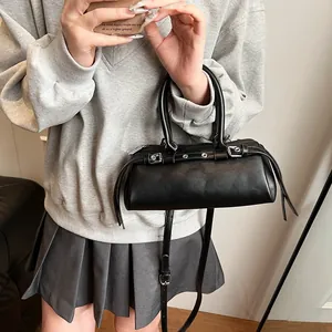 Detail of a black leather baguette bag with silver eyelets and adjustable shoulder strap