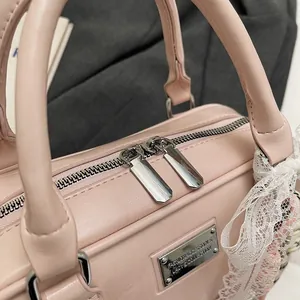 Detail of light pink leather bowling bag with silver zipper and engraved fashion plate