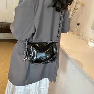 Detail of glossy black crossbody bag with silver chain and cute balloon dog charm