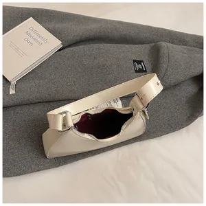 Top view of cream crescent bag showing dark red lining and adjustable metal buckle