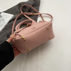 Détail d'un sac seau en cuir rose avec rivets dorés et logo PAN TOR distinctif