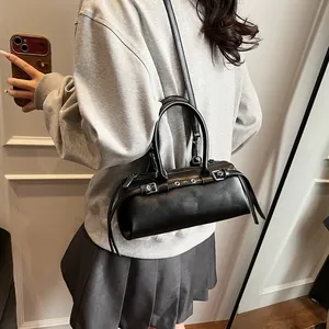 Model styling a black leather cylinder bag with tassel detail and adjustable strap