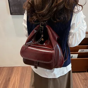 Detail view of burgundy retro backpack featuring glossy finish and metallic buckle accents