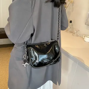 Detail of black glossy shoulder bag with silver chain and cute balloon dog charm