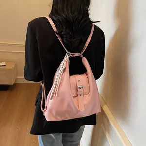 Close-up of pink glossy leather backpack with metallic buckle and woven knot pendant