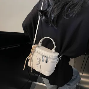 Detail einer cremefarbenen Schminkkoffertasche mit Tragegriff und silbernem Doppelreißverschluss