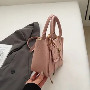 Détail du sac seau rose en cuir litchi avec breloque chat et finitions dorées