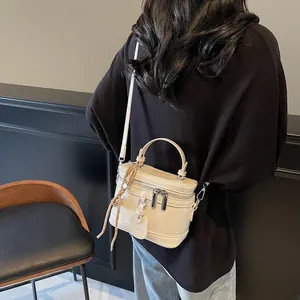 Detailansicht einer cremeweißen Mini-Box-Tasche mit Griff und silbernen Reißverschlüssen