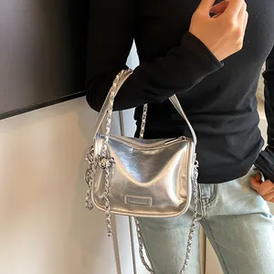 Detail of silver metallic textured crossbody bag with chain strap and fashion logo