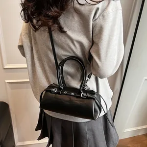 Detail of a black leather barrel bag with silver metal eyelets on an adjustable strap