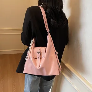 Detail of light pink patent leather shoulder bag with metallic buckle and striped charm