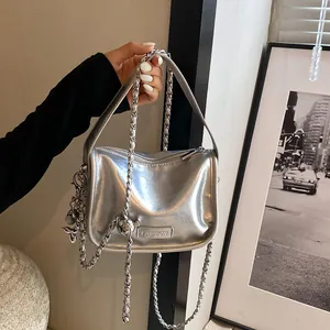 Detail of silver metallic crossbody bag with chain strap and cute balloon dog charm