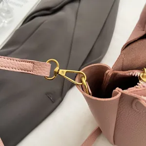 Détail du sac en cuir rose avec fermoir mousqueton doré et connexion de la bandoulière